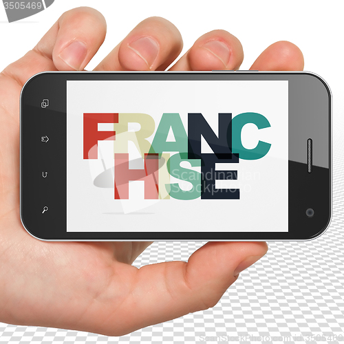 Image of Finance concept: Hand Holding Smartphone with Franchise on  display