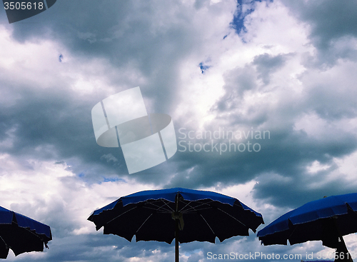 Image of Umbrellas with stormy clouds behind