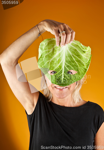 Image of Cute woman holding a cabbage as a mask