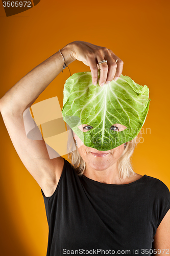 Image of Cute woman holding a cabbage as a mask