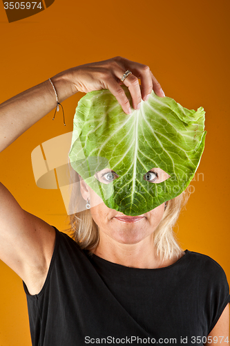 Image of Cute woman holding a cabbage as a mask