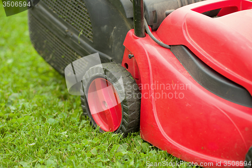 Image of red lawnmower on green grass