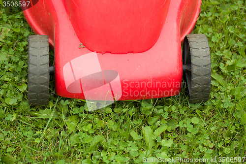 Image of red lawnmower on green grass