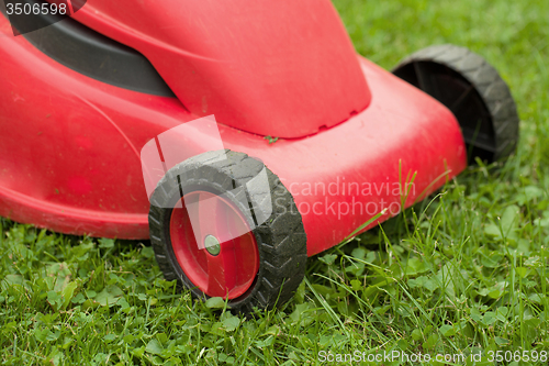 Image of red lawnmower on green grass