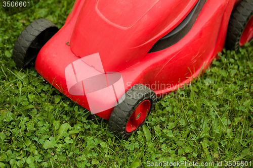 Image of red lawnmower on green grass