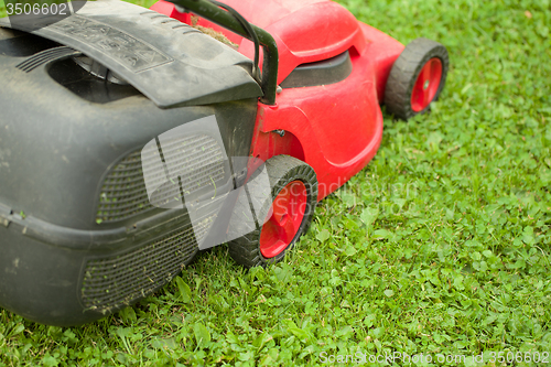 Image of red lawnmower on green grass