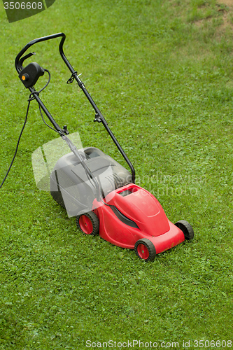 Image of red lawnmower on green grass