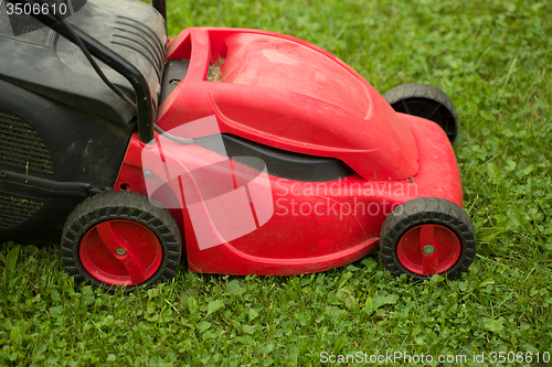 Image of red lawnmower on green grass