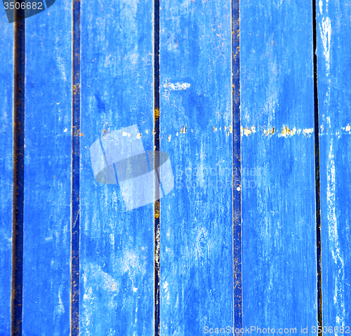 Image of stripped paint in the blue wood door and rusty nail