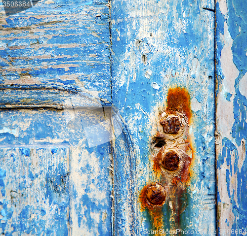 Image of stripped paint in the blue wood door and rusty nail