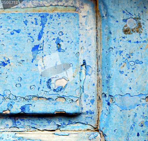 Image of stripped paint in the blue wood door and rusty nail