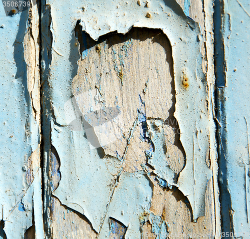 Image of stripped paint in the blue wood door and rusty nail