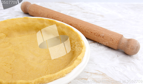 Image of Pie dish lined with pastry with a rolling pin