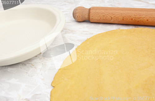 Image of Pastry rolled out with rolling pin next to pie dish