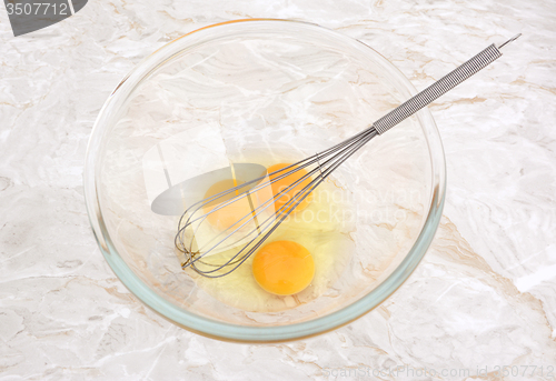 Image of Three eggs in a glass bowl with a whisk