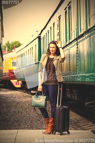 Image of pretty woman with a suitcase and handbag standing near retro rai