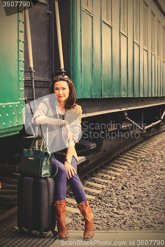 Image of woman with a suitcase and handbag sitting on the steps of the pa