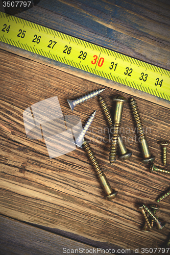 Image of several different screws and yellow measuring tape