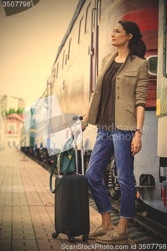Image of beautiful middle-aged woman with luggage rides in retro trip