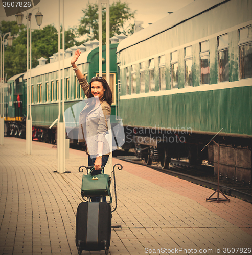 Image of smiling beautiful middle-aged woman with a suitcase and handbag