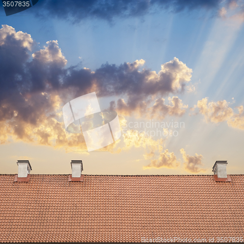 Image of cloudy blue sky and tiled roof top