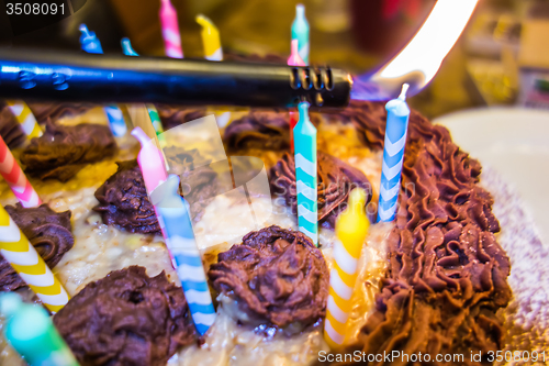 Image of lighting Colorful candles on birthday cake  