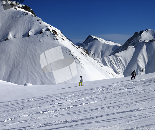 Image of Snowboarders downhill on off piste slope at sun day