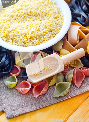 Image of assortment of raw pasta and wheat on wooden background