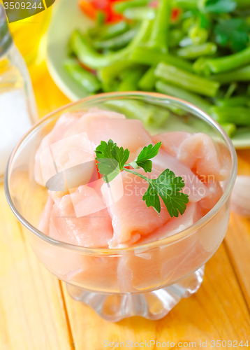 Image of raw chicken and raw vegetables on wooden table