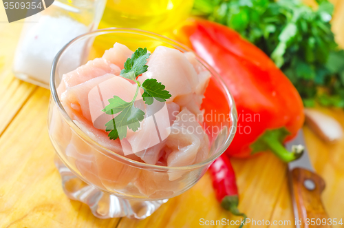 Image of raw chicken and raw vegetables on wooden table