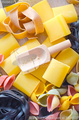 Image of assortment of raw pasta and wheat on wooden background