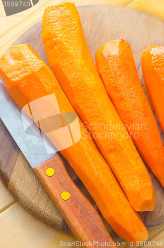 Image of raw carrots and knife on the wooden board