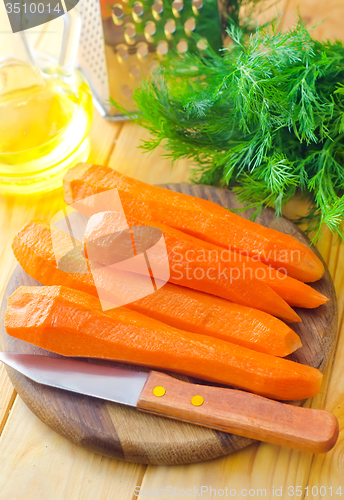 Image of raw carrots and knife on the wooden board