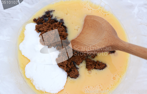 Image of Mixing muscovado and caster sugar into beaten eggs