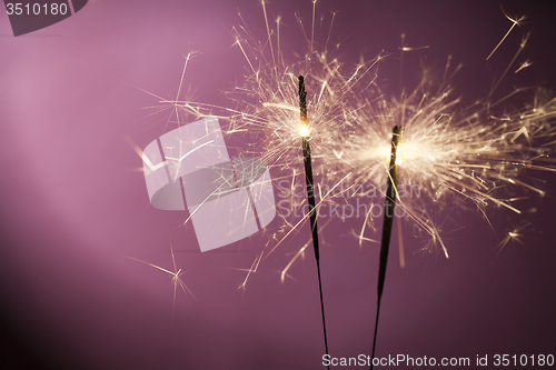 Image of Burning sparklers on pink background