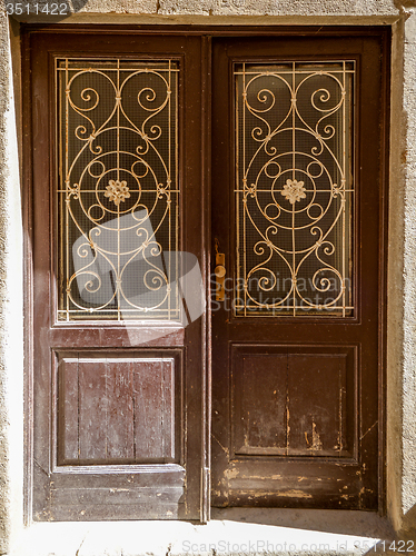 Image of old ragged shabby wooden door with wrought iron bars