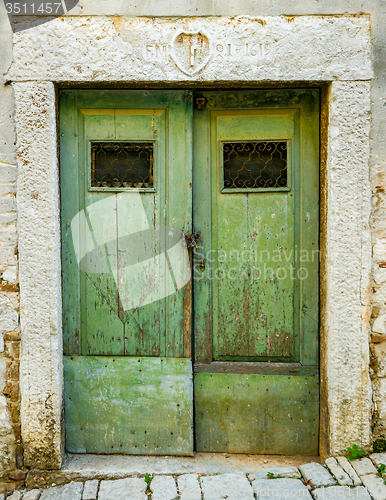 Image of old green ragged shabby wooden door with wrought iron bars
