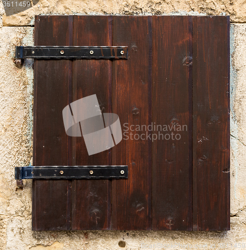 Image of old window with  closed brown  wooden shutters