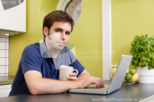 Image of Young Man with Warm Drink at Computer