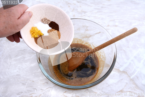 Image of Woman adding spices to pumpkin pie filling