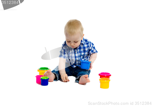 Image of little boy in checkered shirt plays on the floor. Studio