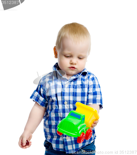Image of little boy in checkered shirt plays with a toy car
