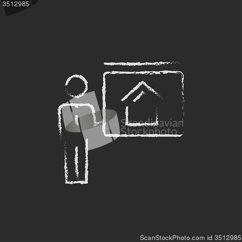 Image of Real estate agent showing the house icon drawn in chalk.