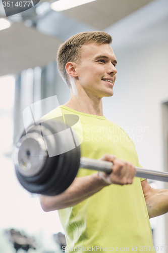 Image of smiling man doing exercise with barbell in gym