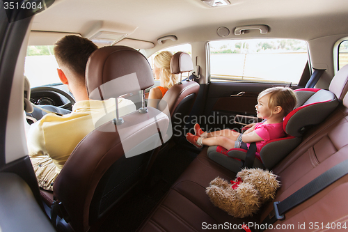 Image of happy parents with little child driving in car
