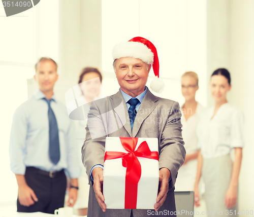 Image of smiling man in suit and santa helper hat with gift