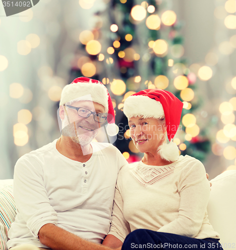 Image of happy senior couple in santa helper hats