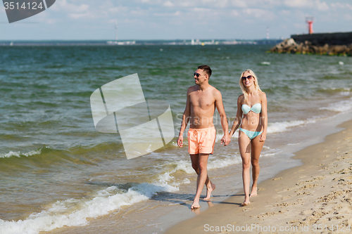 Image of happy couple in swimwear walking on summer beach