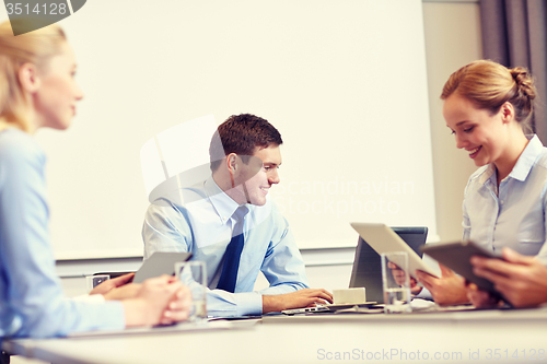 Image of smiling business people with tablet pc in office