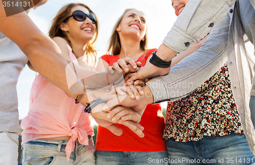 Image of close up of happy friends with  hands on top 